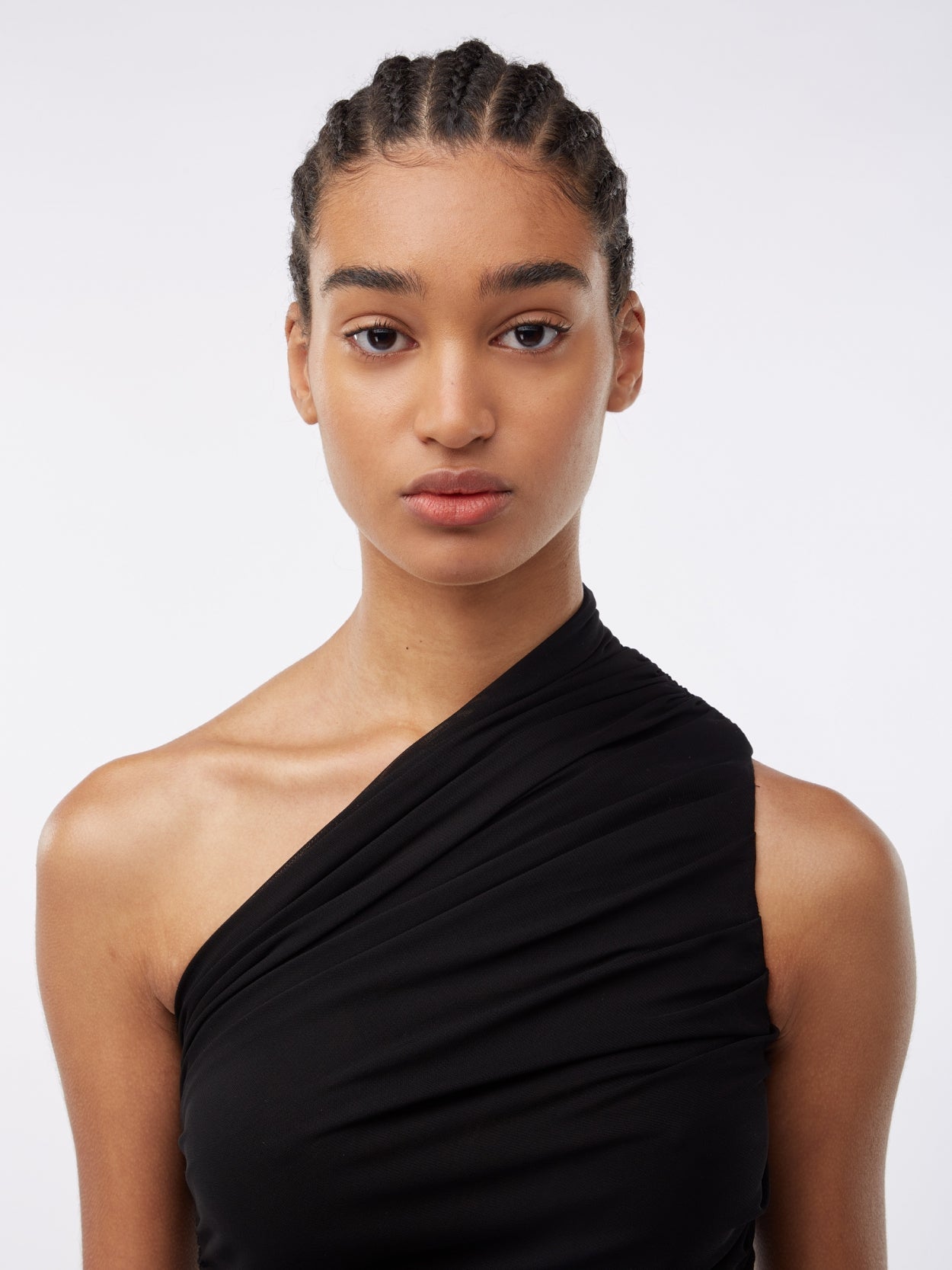 close up of a model wearing a one shoulder black draped dress