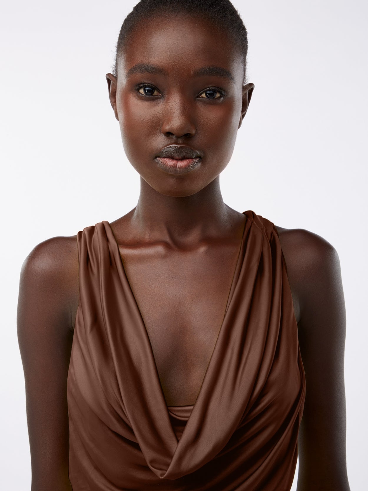 close up of a model wearing a brown long draped jersey dress