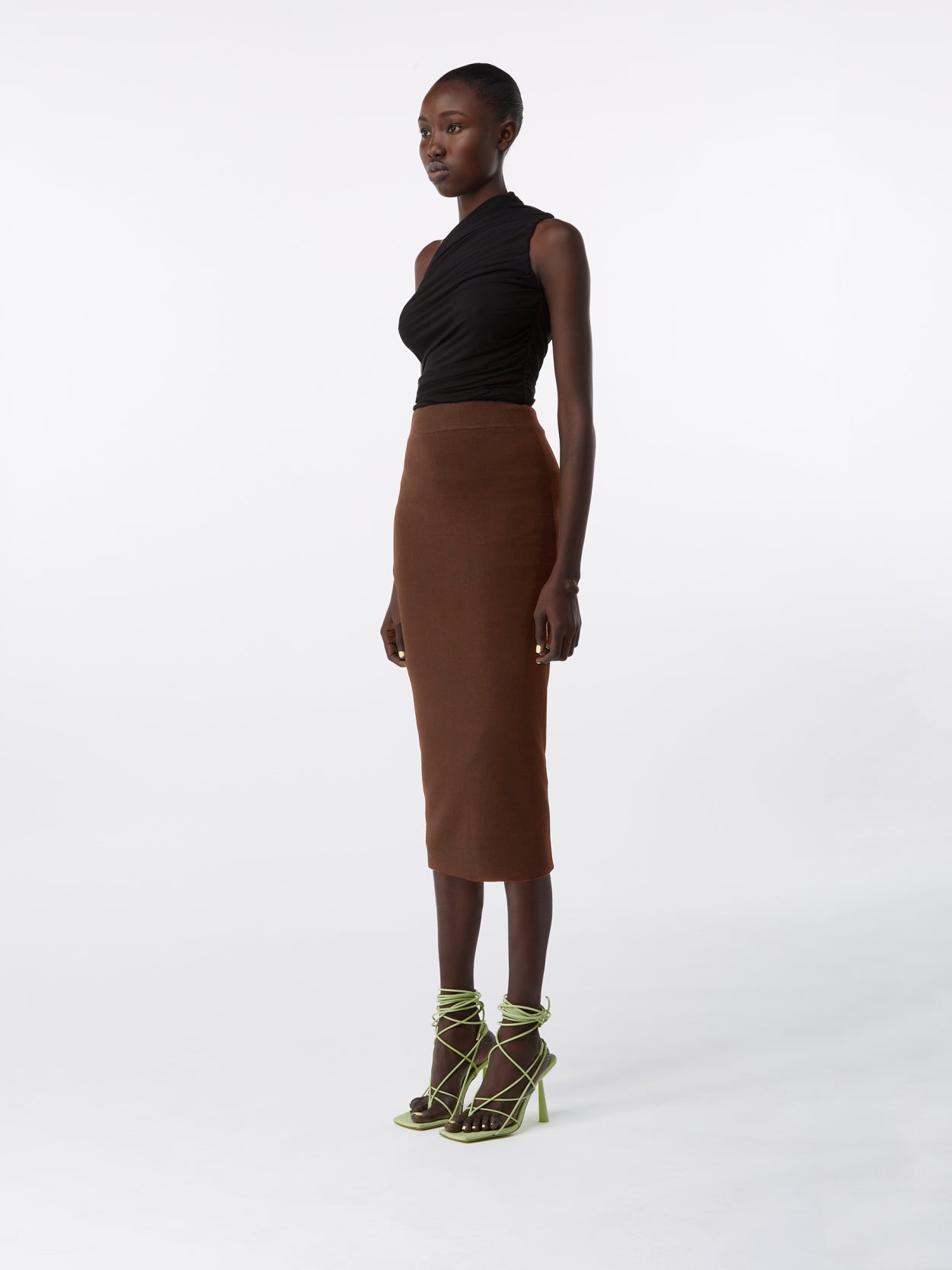 model wearing a black one shoulder draped jersey bodysuit and a brown midi knit pencil skirt
