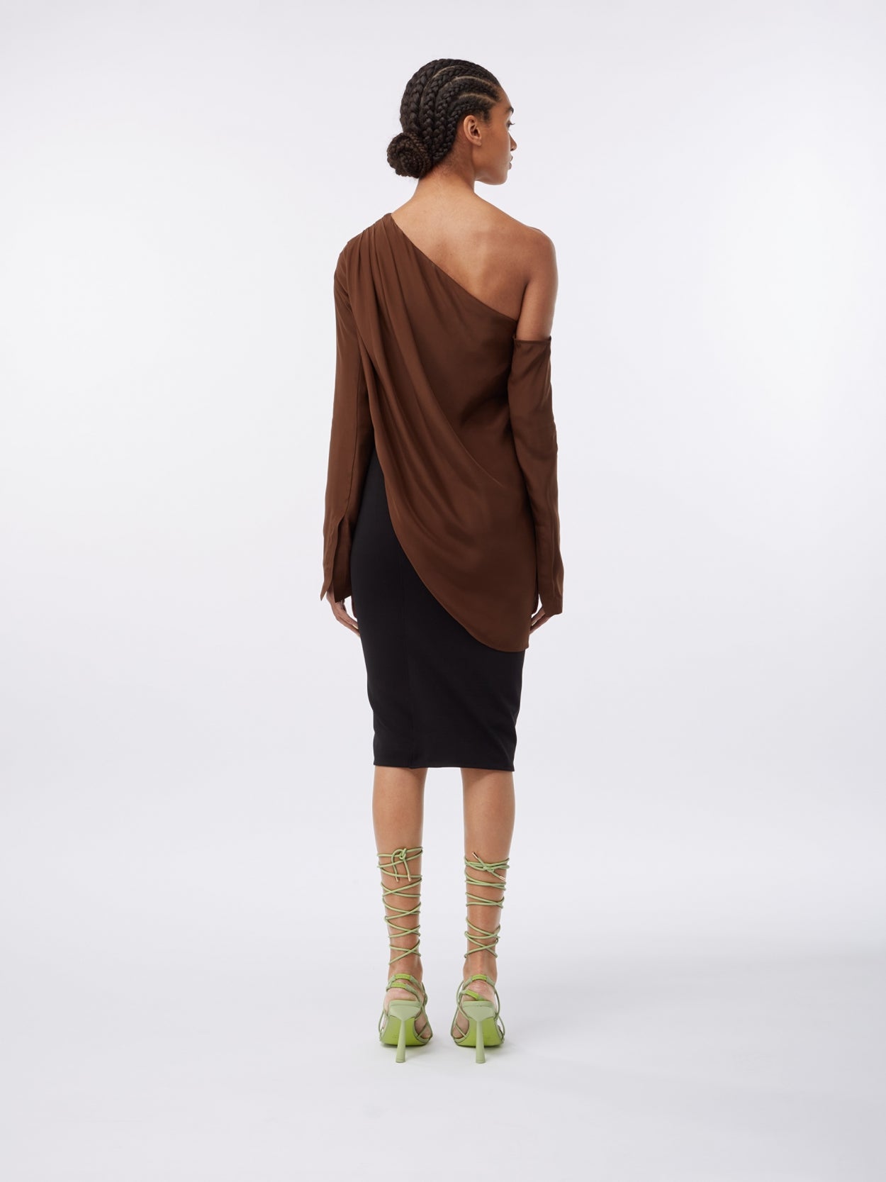 model wearing a brown asymmetric long sleeve silk top and a black midi pencil skirt with waist strap