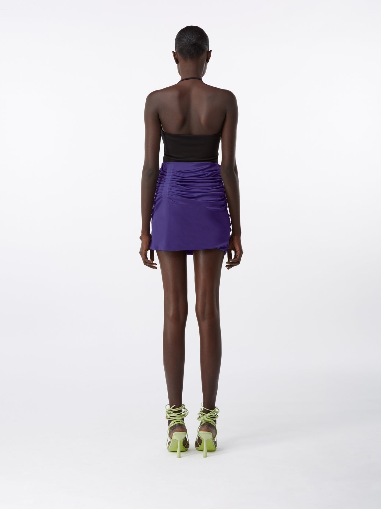 model wearing a purple draped skirt and a black shifted halter bodysuit